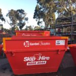 Red JP Garden Supplies skip hire bin sitting on road